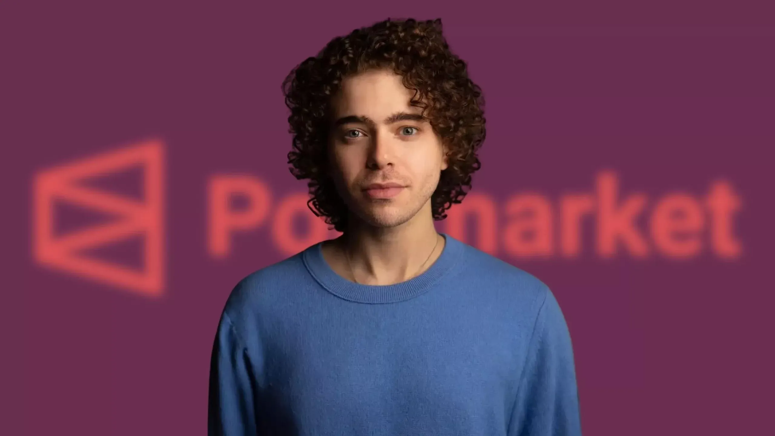Polymarket founder Shayne Coplan standing in front of the Polymarket logo on a purple background
